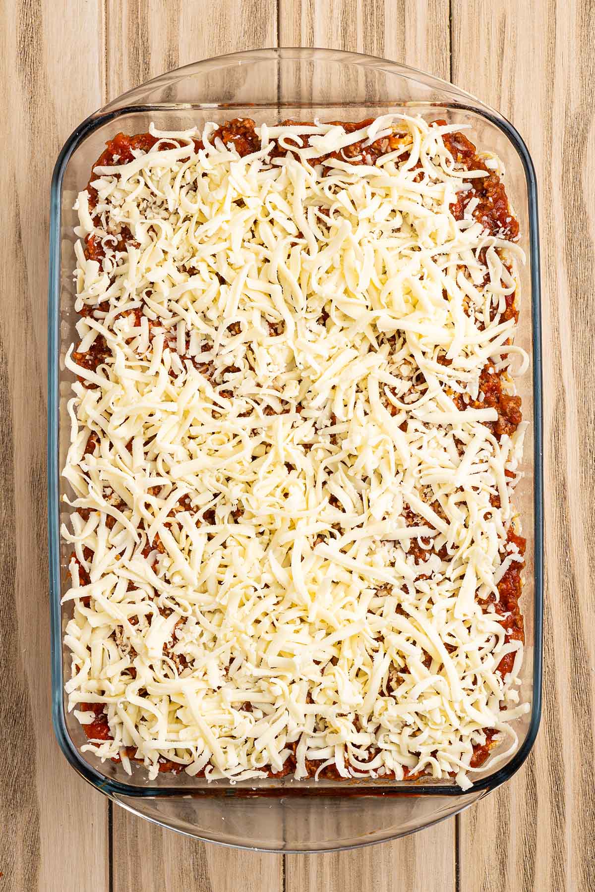 Shredded mozzarella sprinkled evenly over the meat sauce, ready to bake.