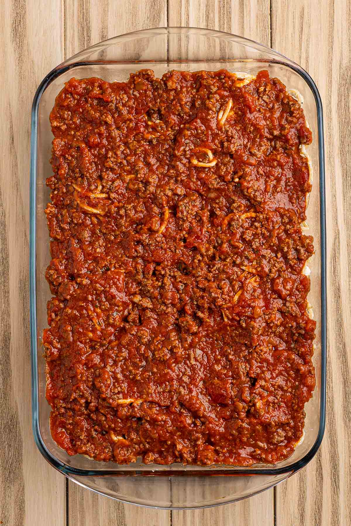 Meat sauce spread evenly over the cream cheese spaghetti layer.