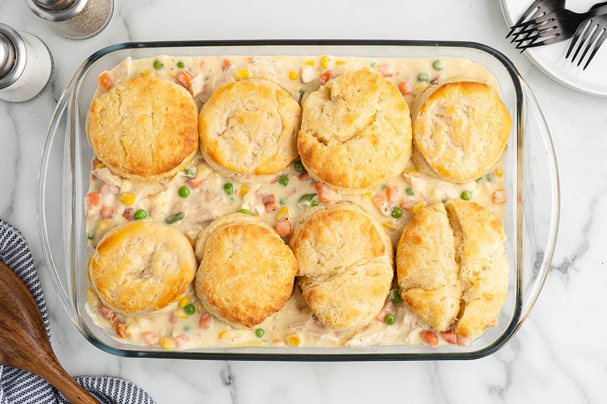 Overhead view of baked chicken pot pie casserole with golden biscuits on top.