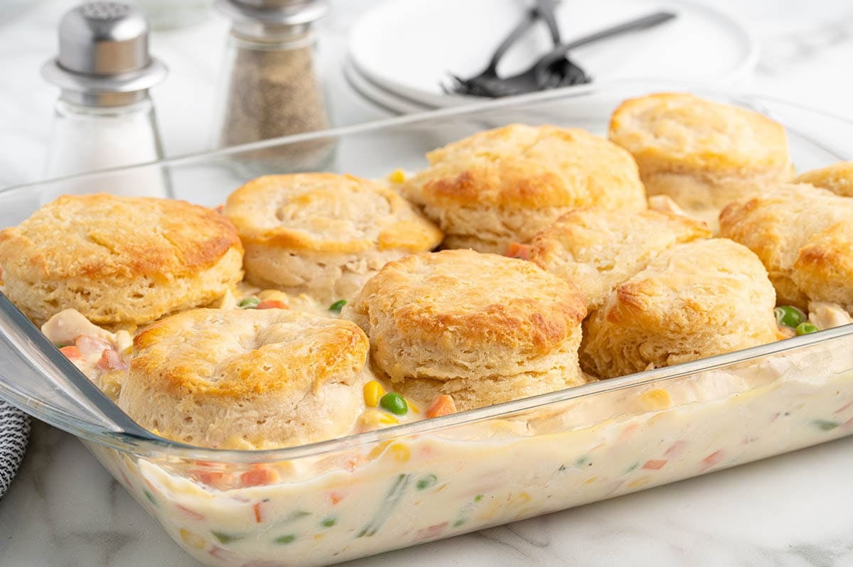 Chicken pot pie casserole topped with golden baked biscuits in a glass dish.