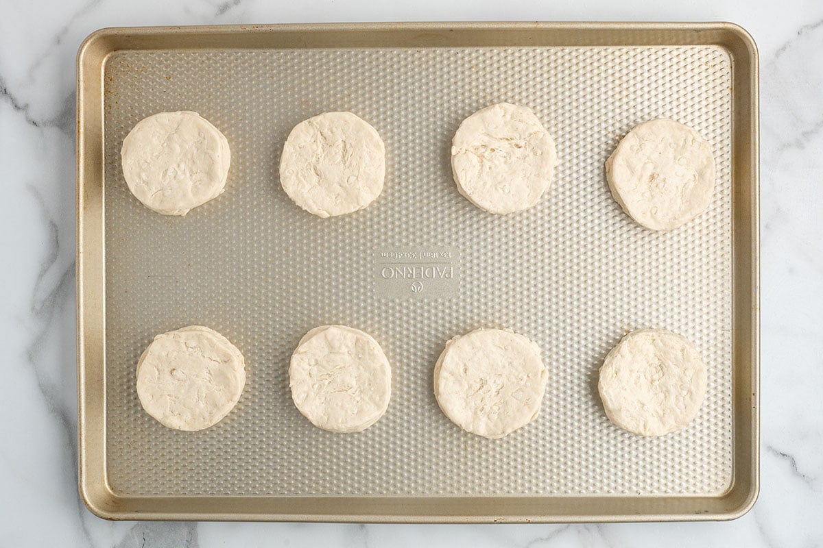 Refrigerated biscuit dough rounds arranged on a baking sheet before baking.