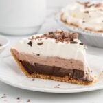 Slice of layered chocolate pudding pie topped with whipped cream and chocolate shavings.
