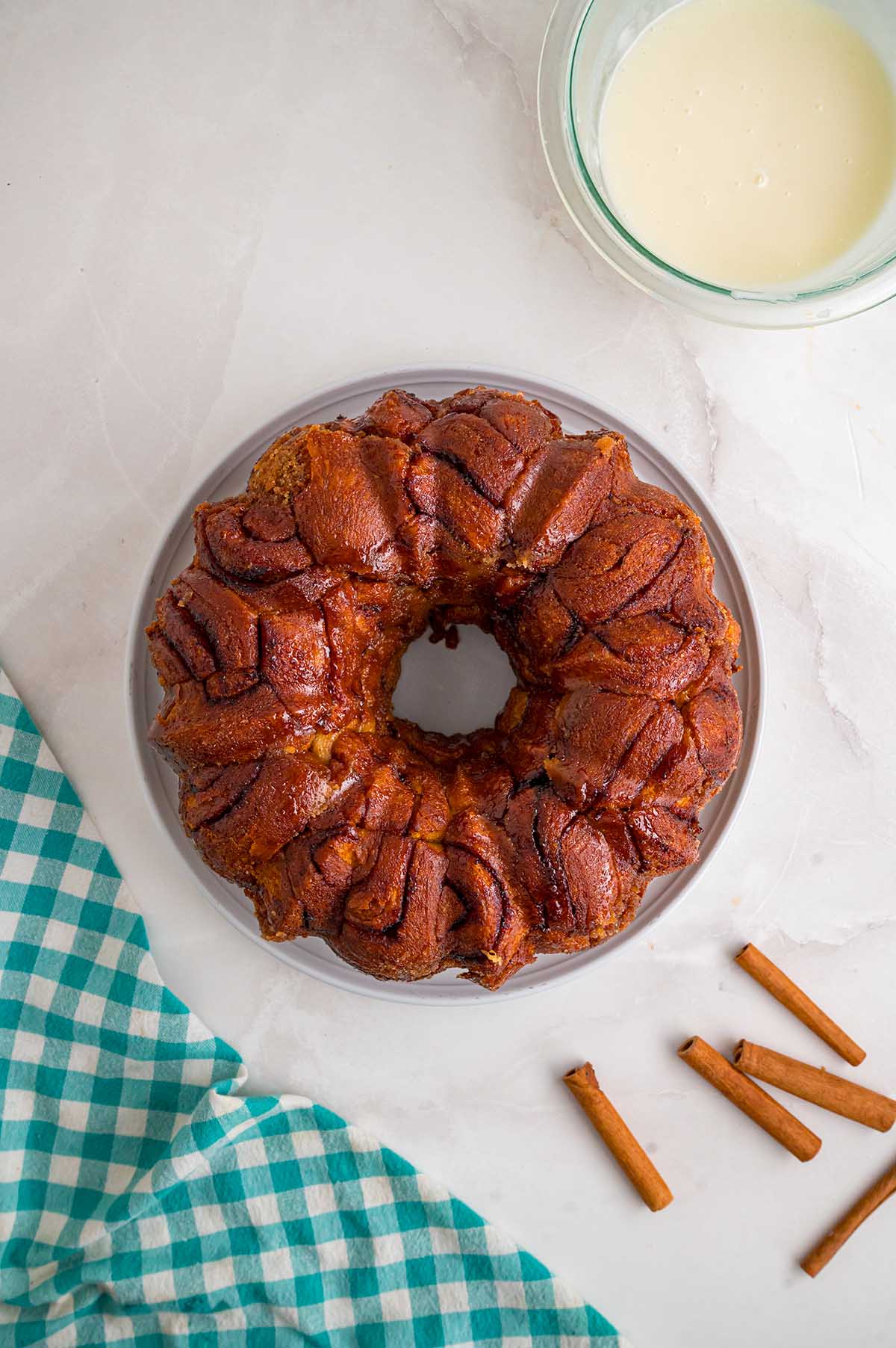 Freshly baked cinnamon roll monkey bread turned onto a plate with vanilla glaze ready for drizzling.
