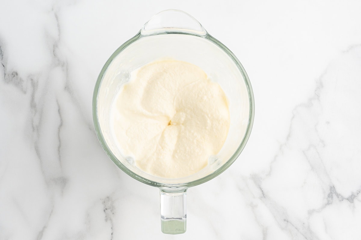 Overhead view of smooth pineapple Dole Whip mixture blended in a glass blender pitcher.