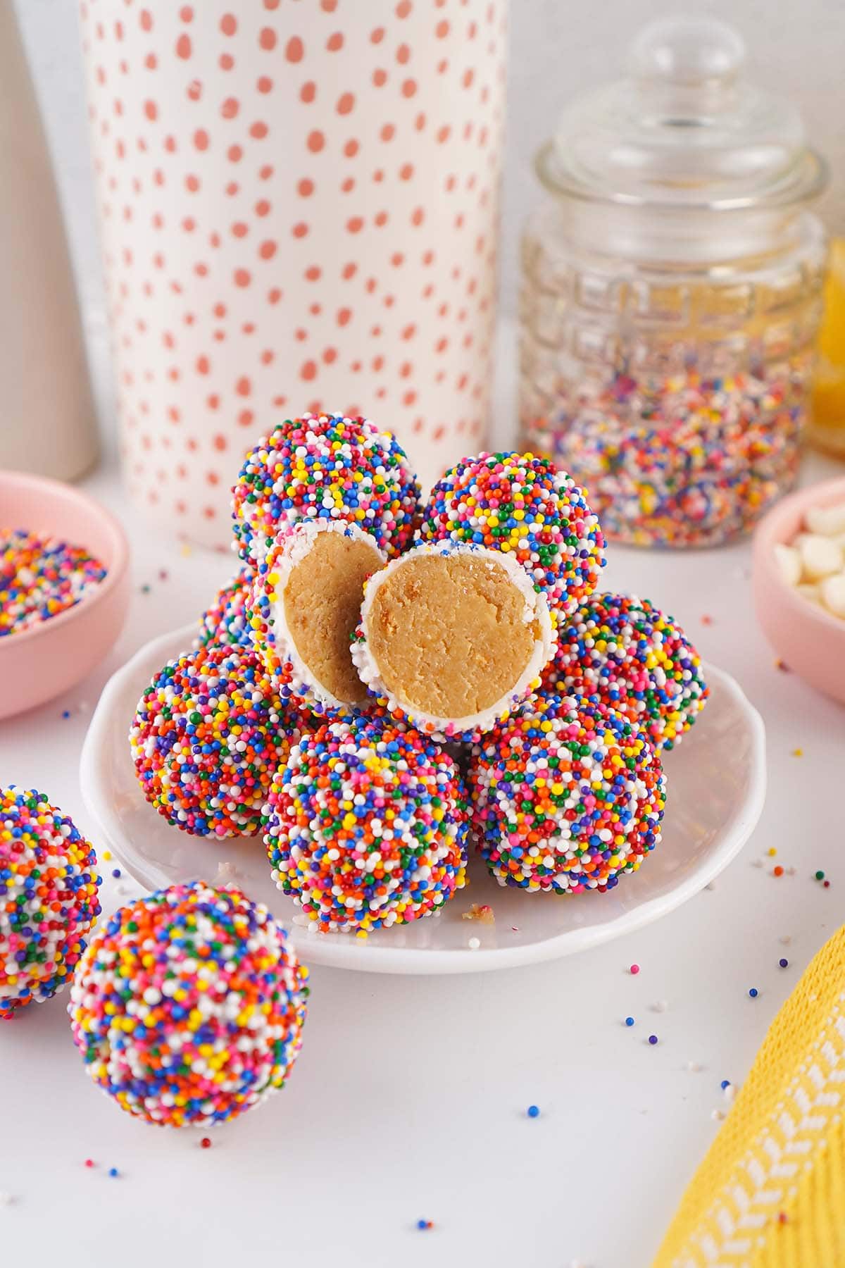 Sprinkle covered cake bites on a plate with one cut open to reveal the soft cake center.