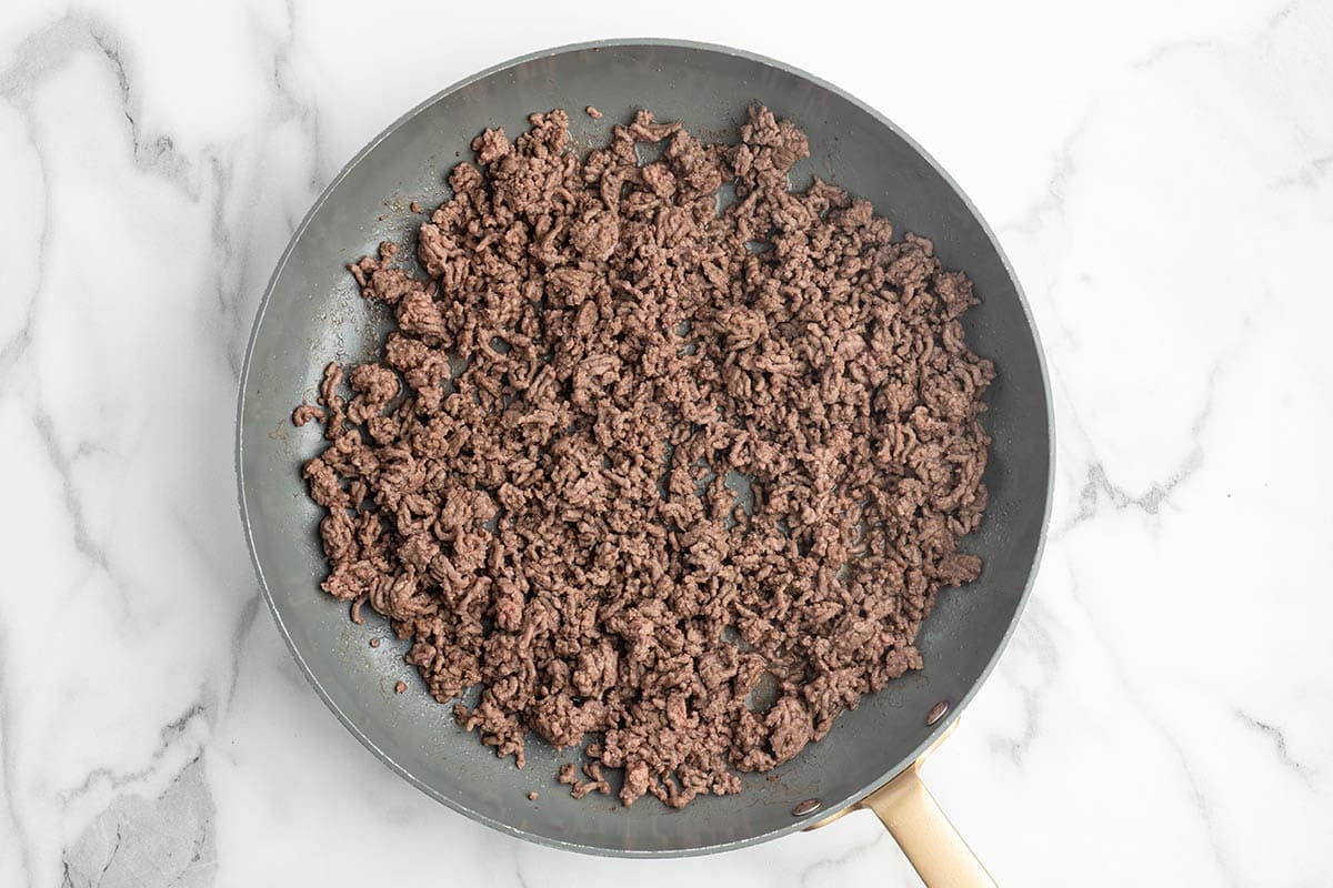 Ground beef browning in a skillet.