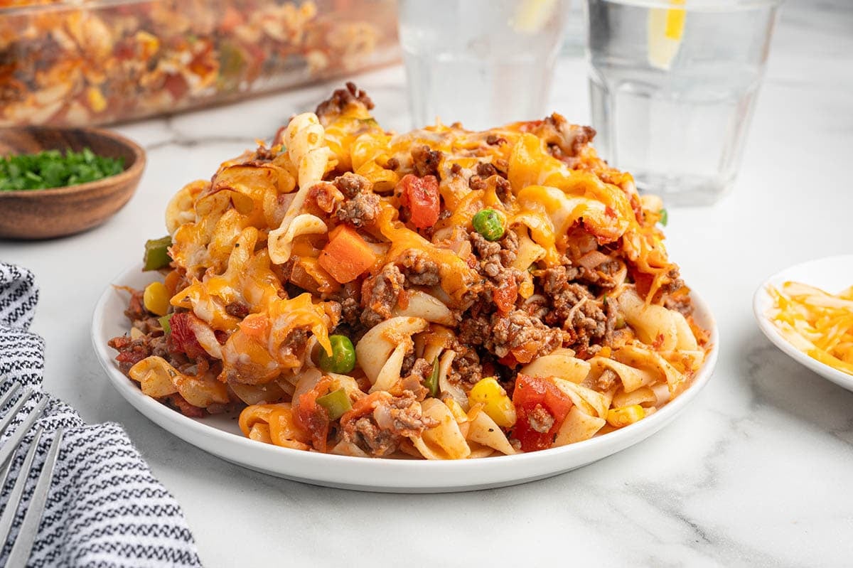Plated serving of hamburger casserole with egg noodles, ground beef, vegetables, and cheese.