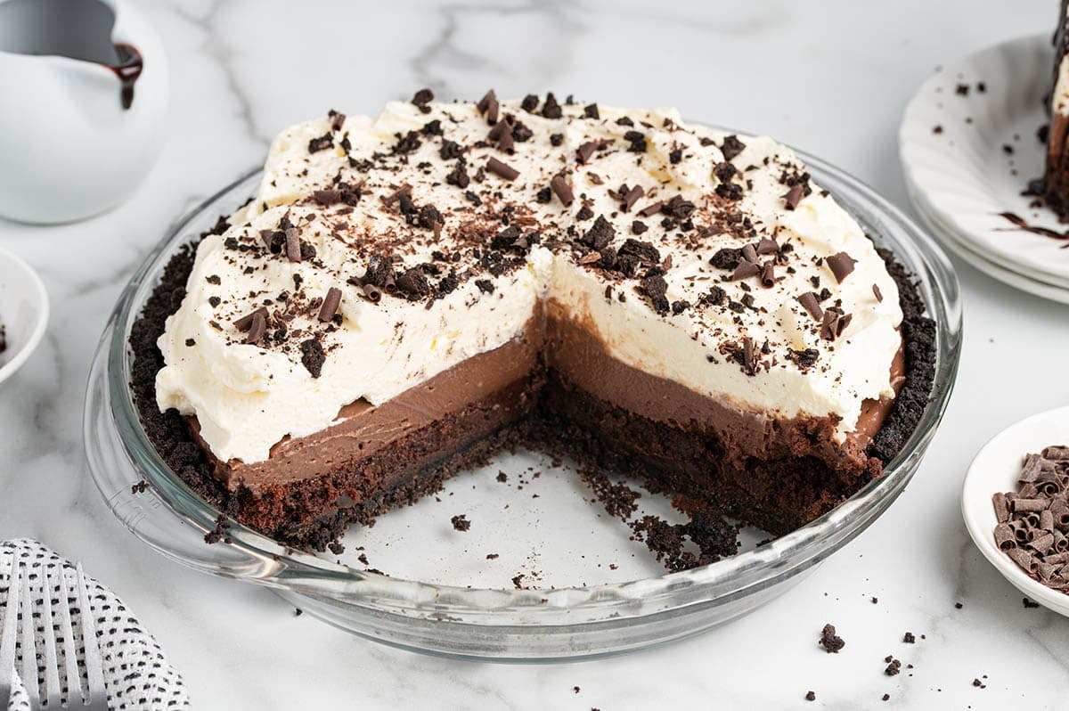 Whole mud pie with a slice removed, showing the Oreo crust and layered chocolate filling.