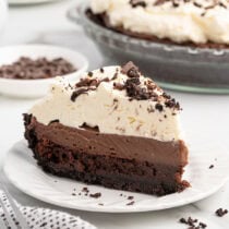"Slice of mud pie with an Oreo crust, chocolate filling, and whipped cream topped with chocolate curls.