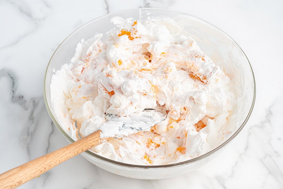 Fold whipped topping into the orange mixture in a large glass bowl until fluffy and combined.