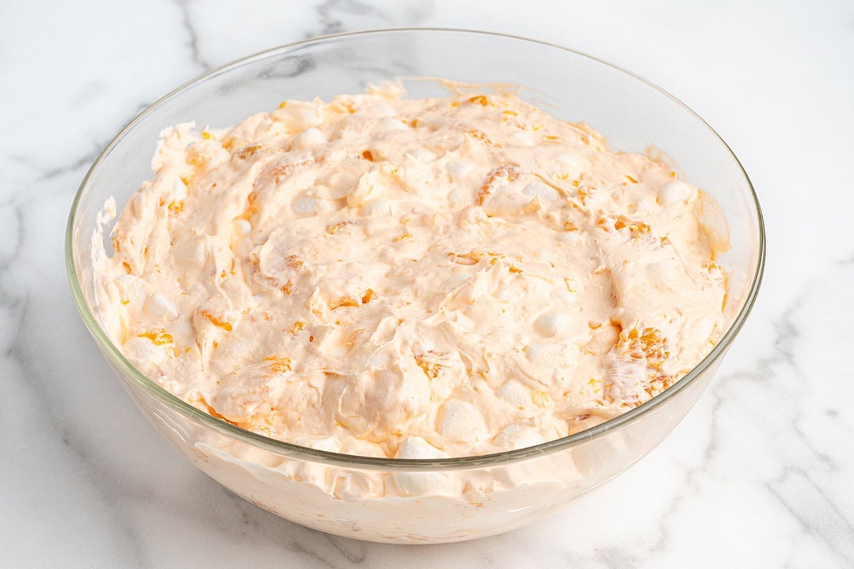Orange Creamsicle Salad chilled in a large glass bowl, ready to garnish and serve.