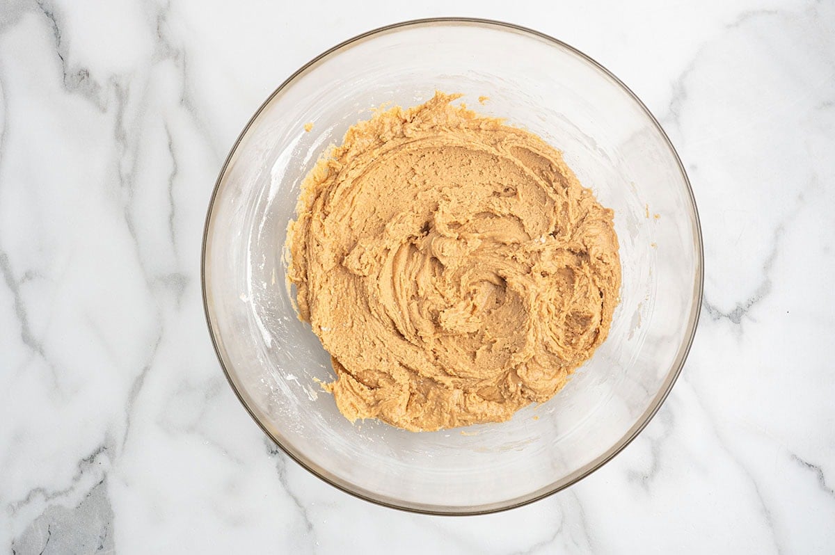 Peanut butter mixture in a glass bowl, ready to be rolled into balls.