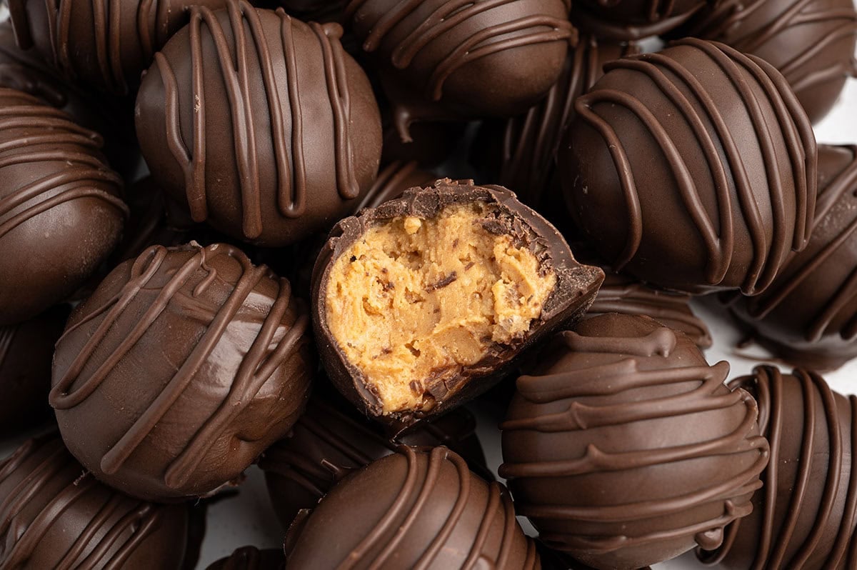 Close-up of chocolate-drizzled peanut butter Rice Krispie balls, one sliced open.