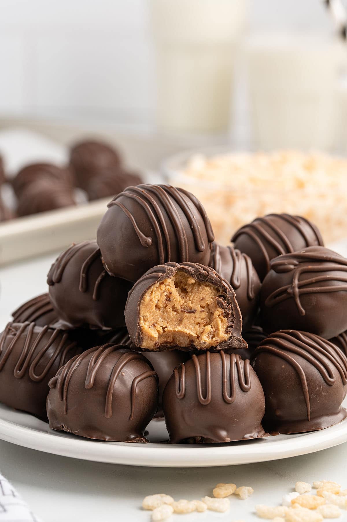 Stacked chocolate peanut butter Rice Krispie balls on a plate, one cut open showing the filling.