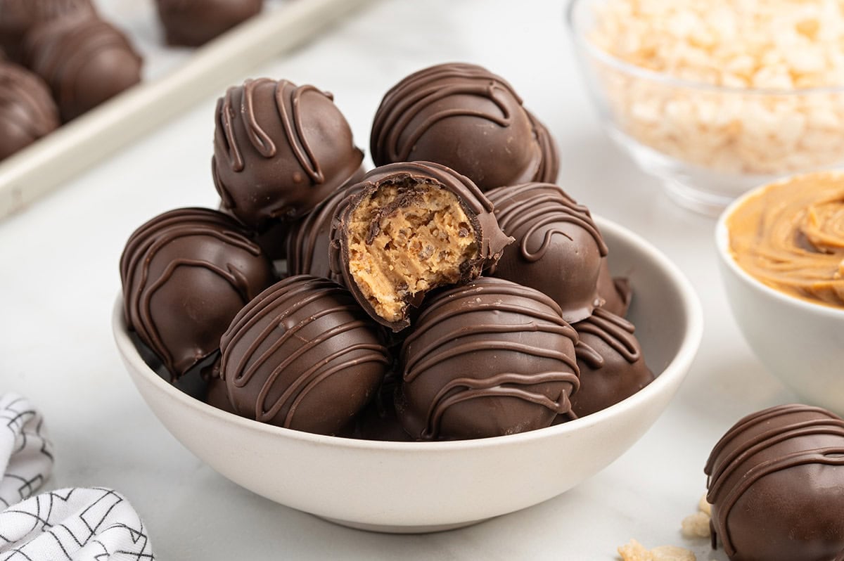 Chocolate-covered peanut butter Rice Krispie balls in a bowl, one bitten in half.