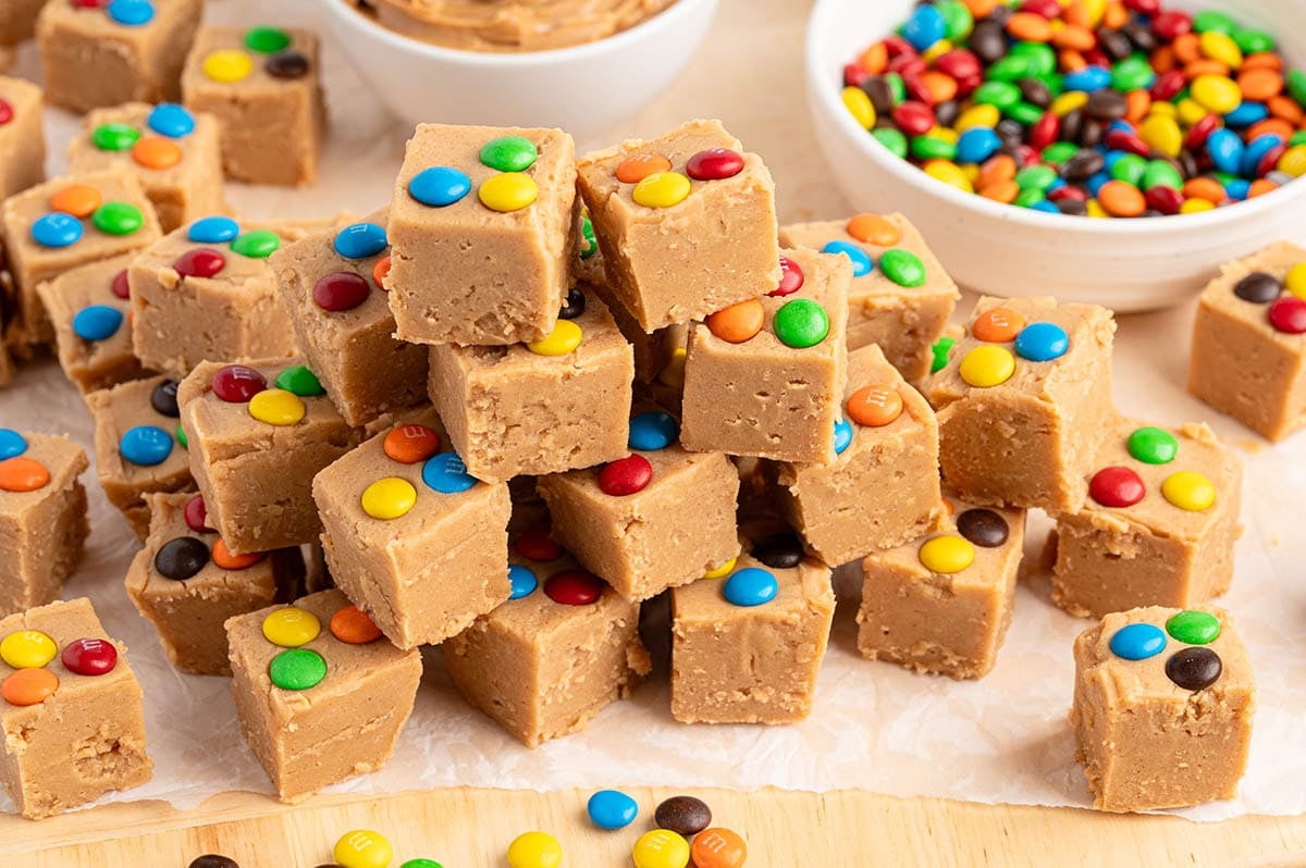 Stack of peanut butter fudge squares topped with colorful M&M's candies.