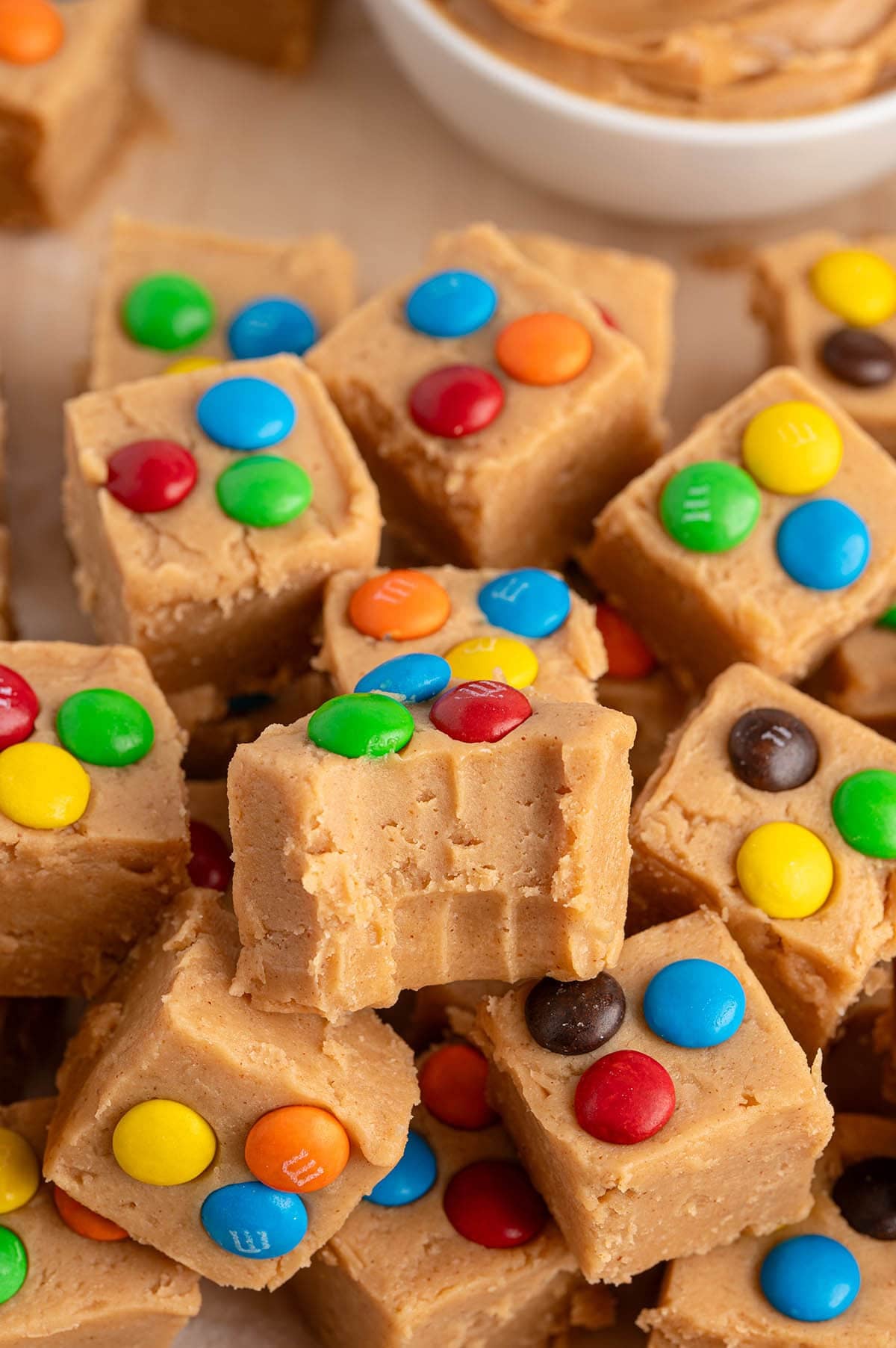 Peanut butter fudge square with a bite taken out, topped with colorful M&M's candies.