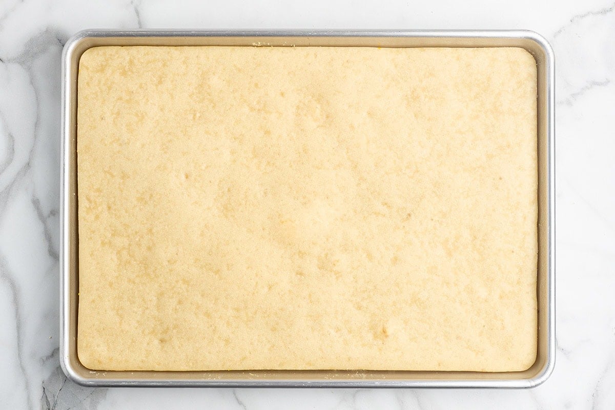 Par-baked rectangular pizza crust on a baking sheet, ready for toppings.