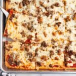 School pizza squares with melted cheese and sausage topping.