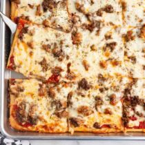 School pizza squares with melted cheese and sausage topping.