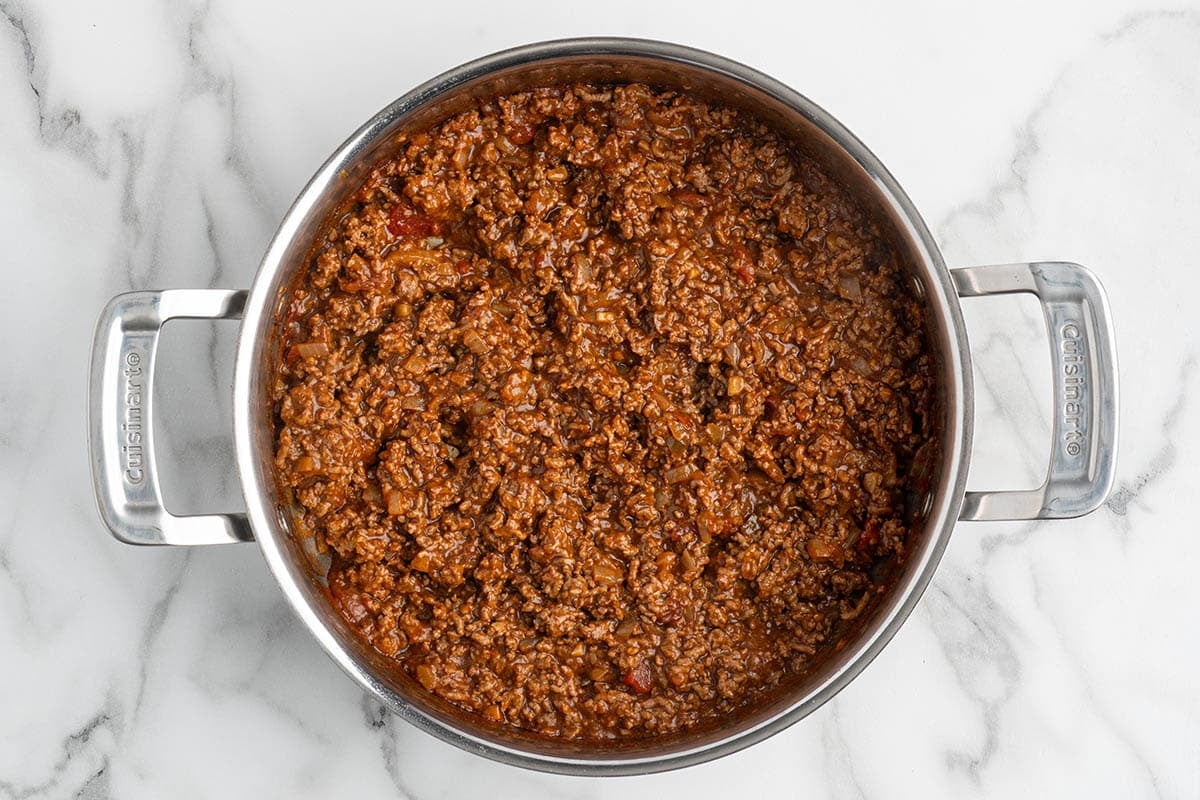Seasoned taco ground beef with salsa cooked in a stainless steel pot.