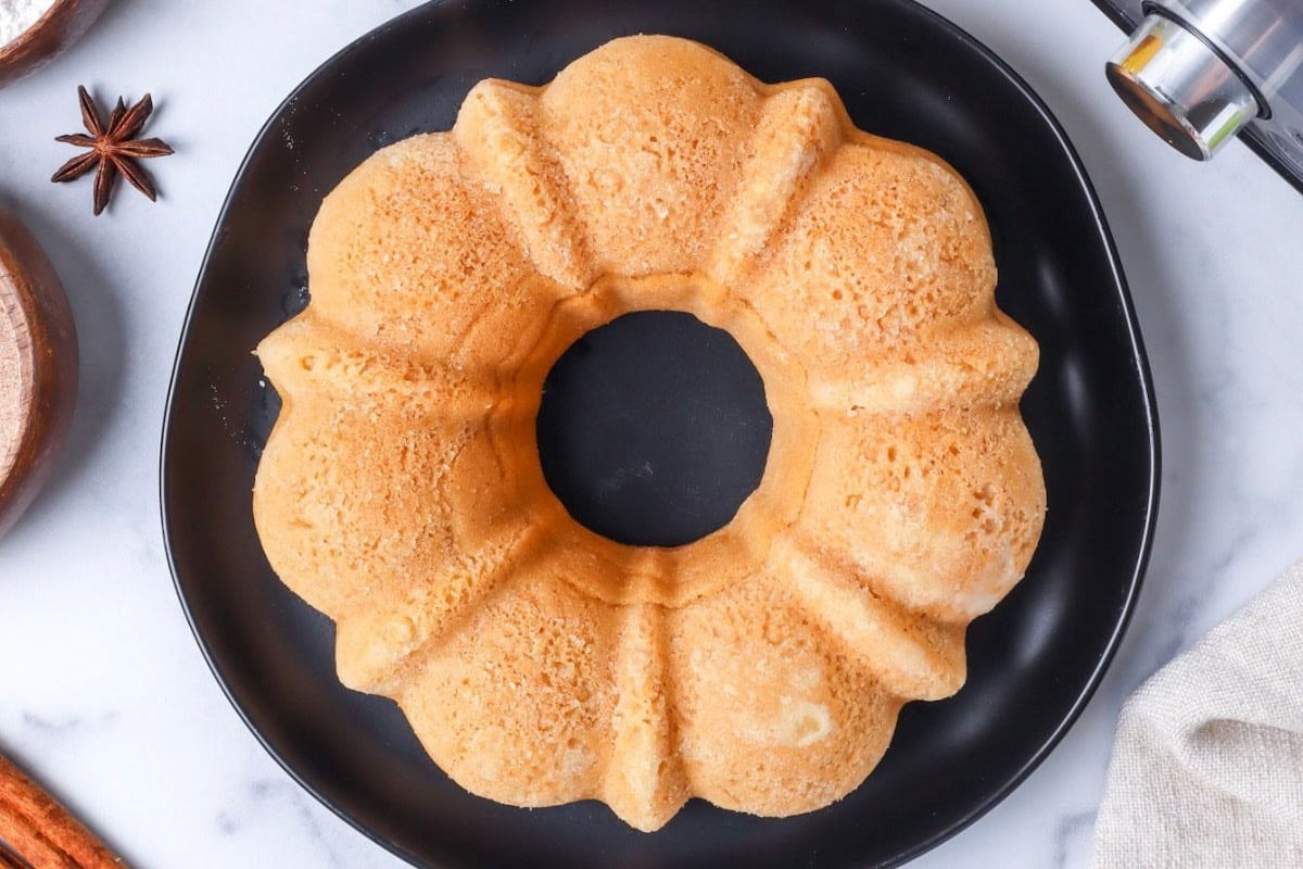 Baked, unglazed Bundt cake on a black plate, viewed from above, with star anise nearby.