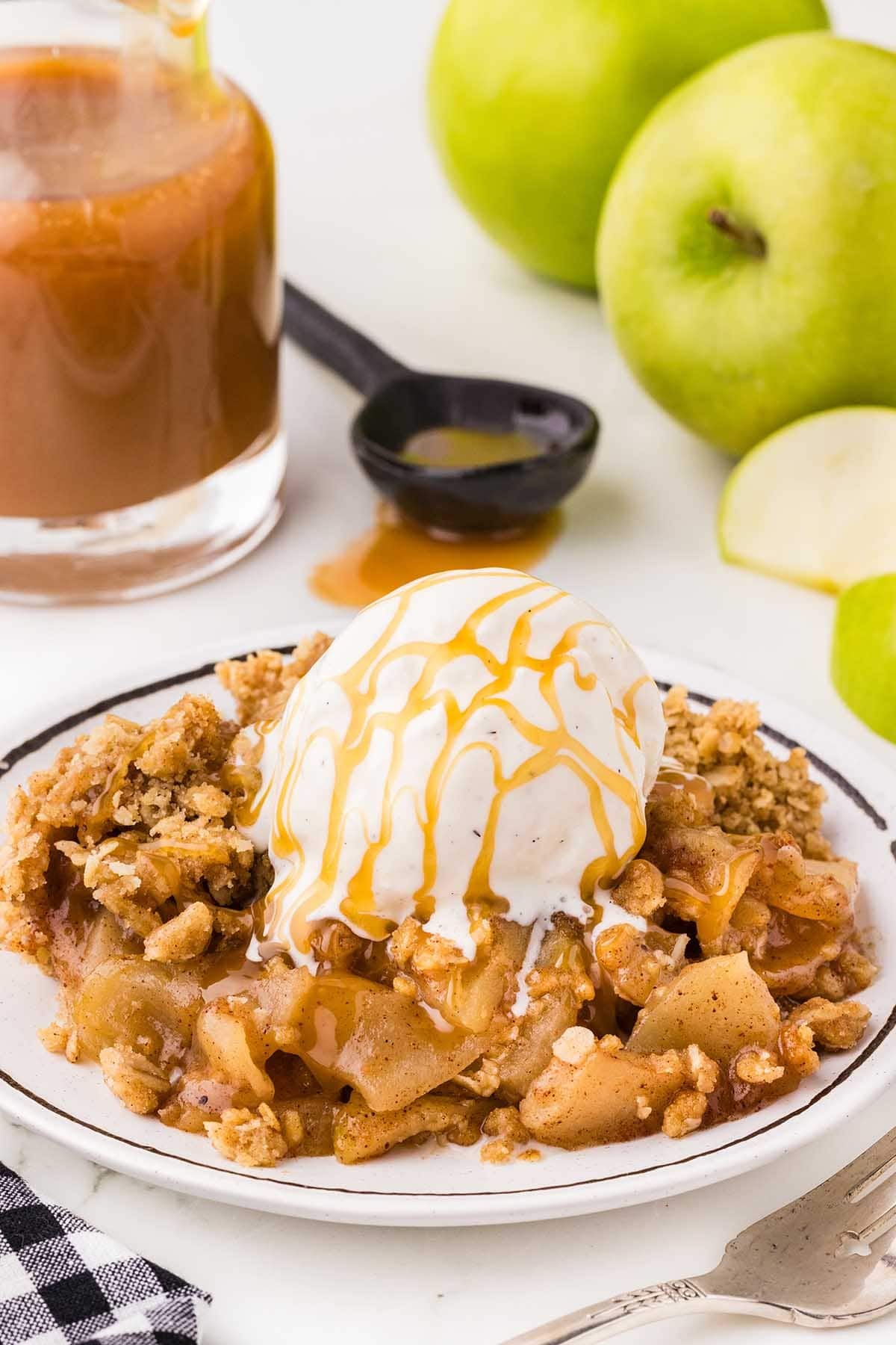 Apple crisp topped with vanilla ice cream and caramel drizzle, served with green apples.
