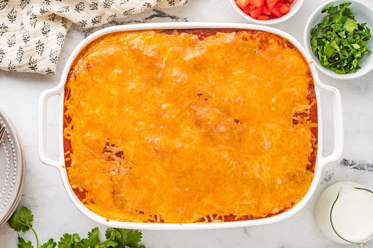 Baked beef enchilada casserole with melted cheddar cheese in a baking dish.