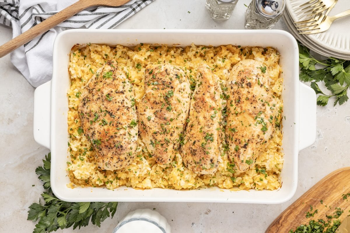 Baked chicken and rice casserole with seasoned chicken breasts in a white dish.