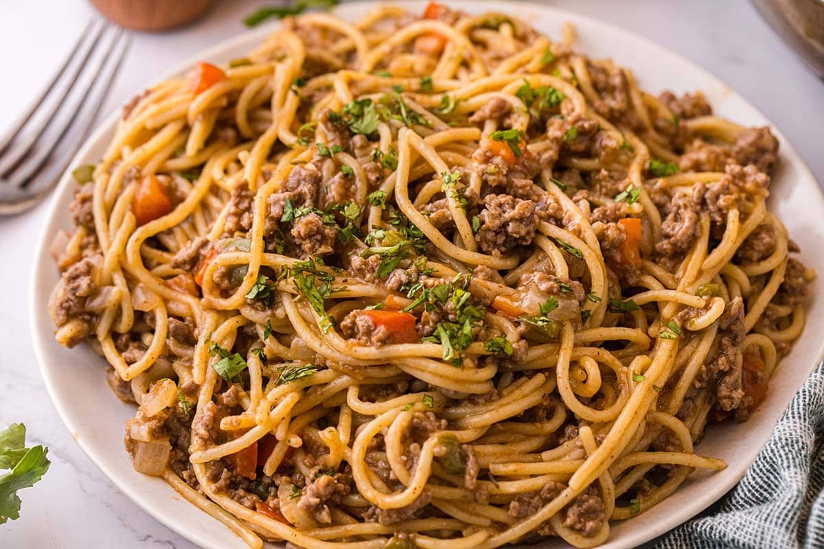Dirty Spaghetti with ground beef, vegetables, and parsley served on a plate.