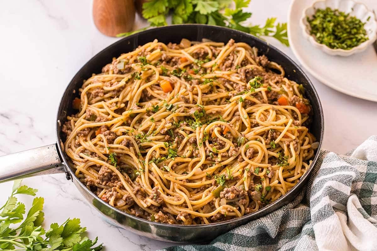 Dirty Spaghetti with ground beef, vegetables, and parsley served in a skillet.