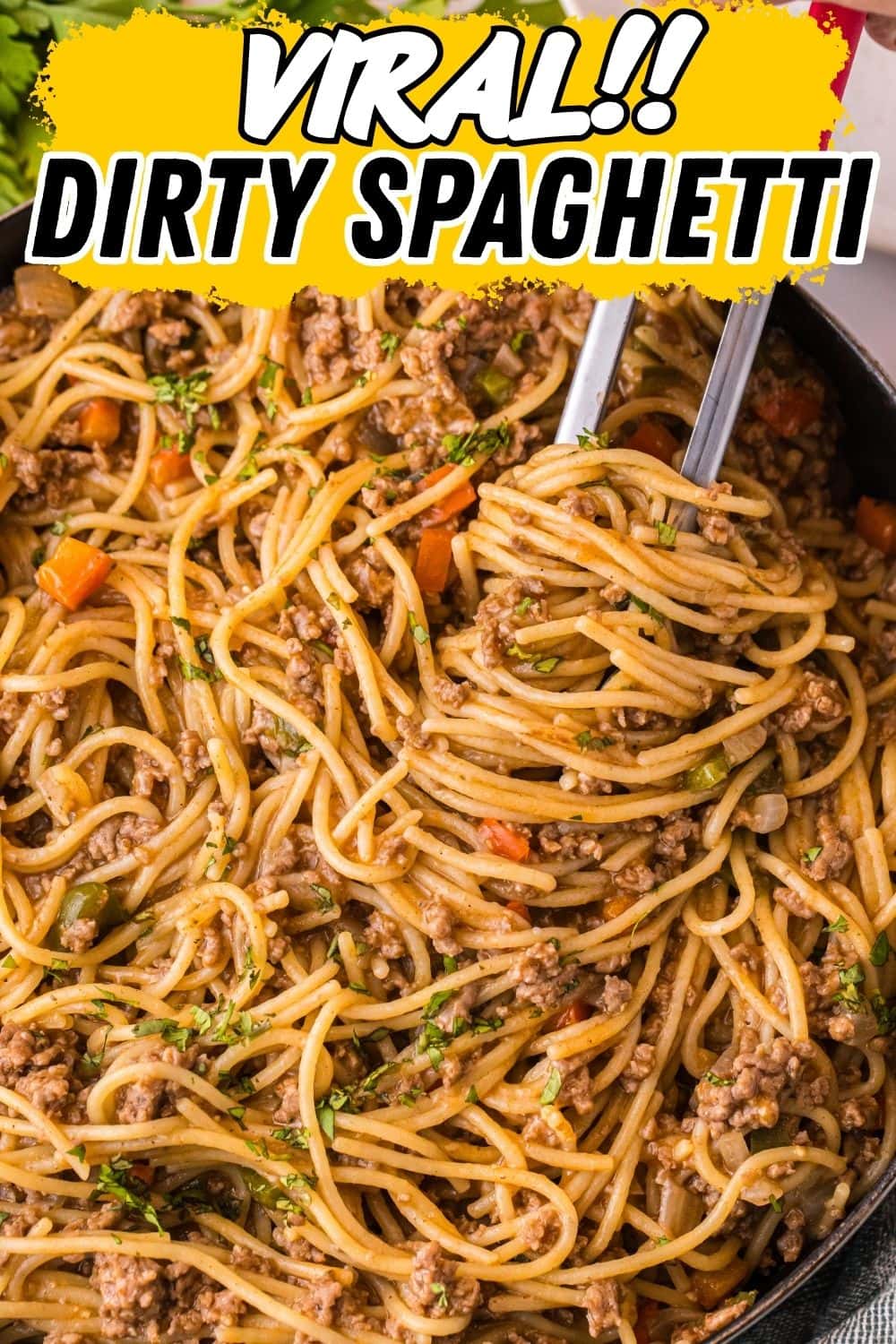 Close-up of tongs lifting dirty spaghetti with ground meat and vegetables from a skillet.