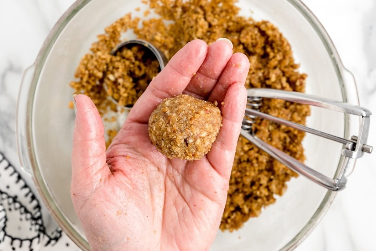 Pecan Pie Balls mixture being shaped into a ball by hand.