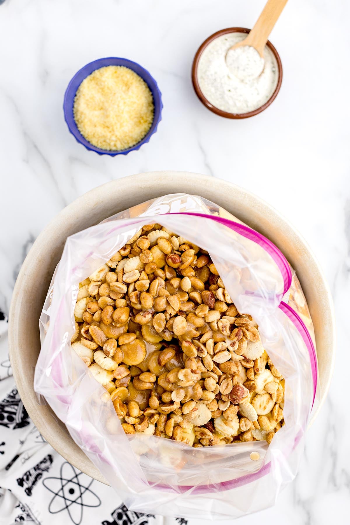 Ranch Chex Mix with peanuts and crackers being seasoned in a large plastic bag.