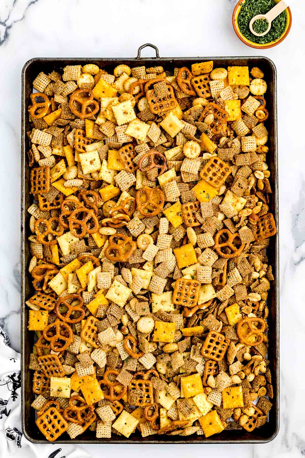 Ranch Chex Mix with pretzels, cereal, crackers, and nuts spread evenly on a baking sheet.