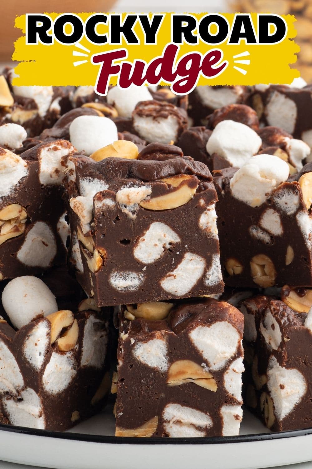 Close-up of rocky road fudge squares stacked with marshmallows and peanuts visible.