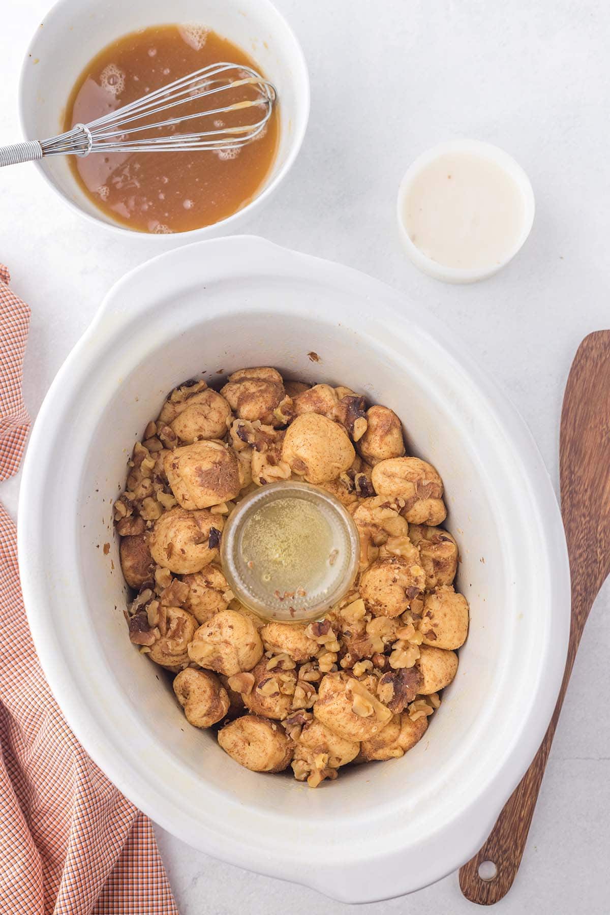Layer coated biscuit dough and chopped walnuts in the slow cooker before pouring over the brown sugar butter sauce.