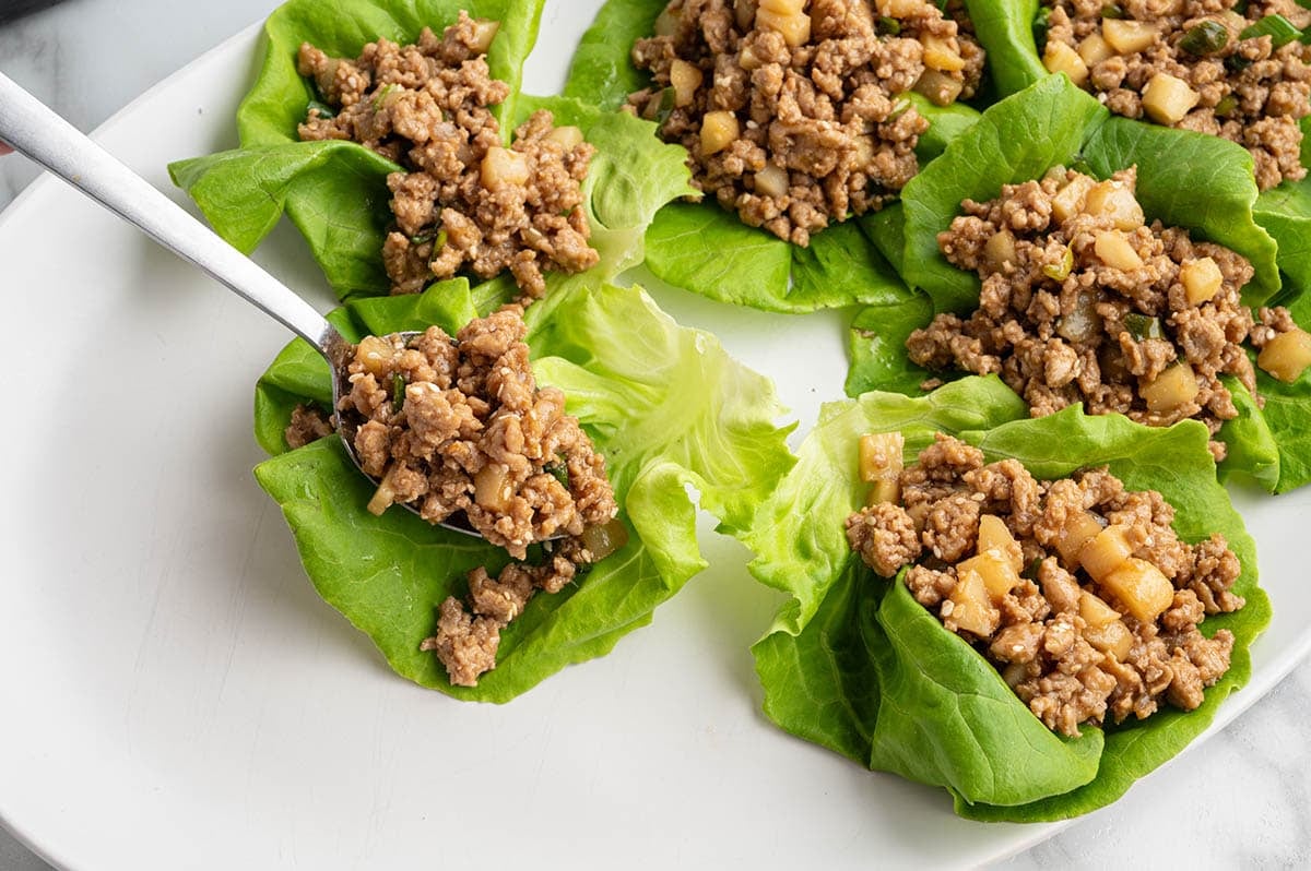 Asian chicken lettuce wraps being filled with ground chicken and water chestnuts.