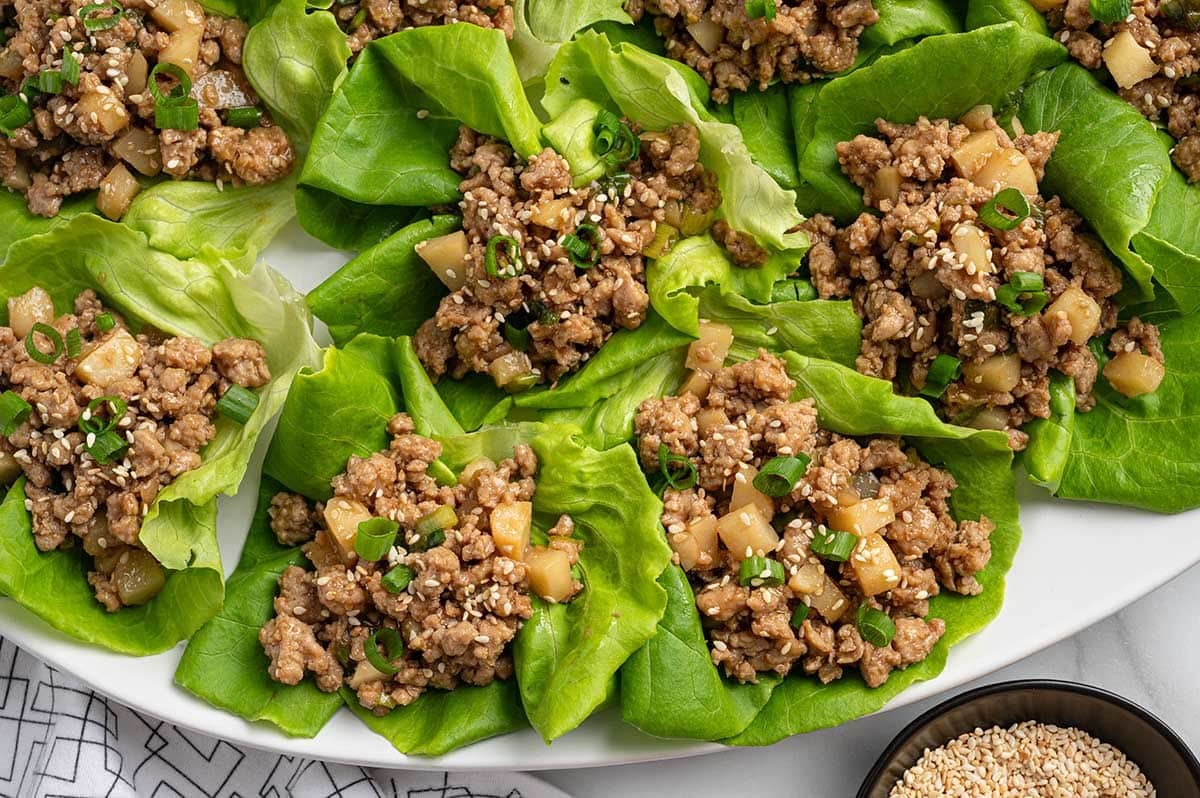 Asian chicken lettuce wraps with ground chicken, water chestnuts, green onions, and sesame seeds.