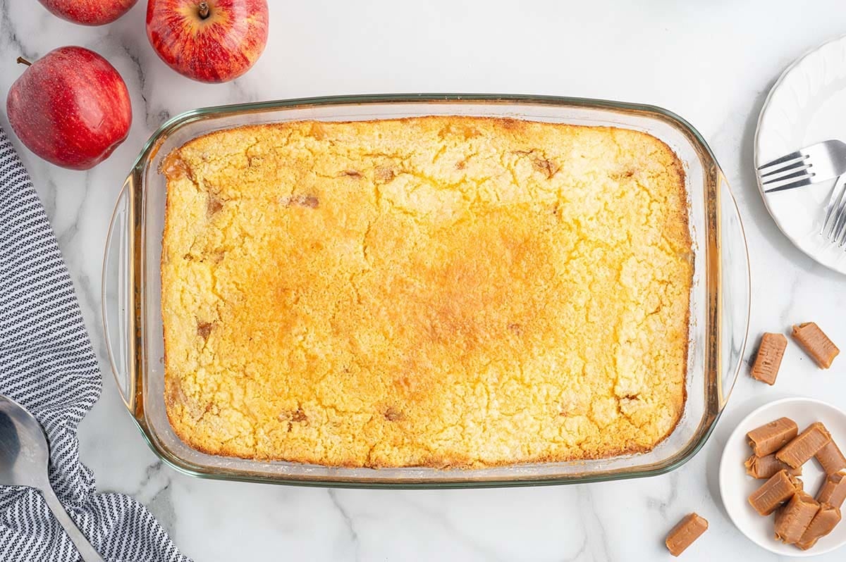 Overhead view of baked caramel apple dump cake with golden cake topping in a glass dish.
