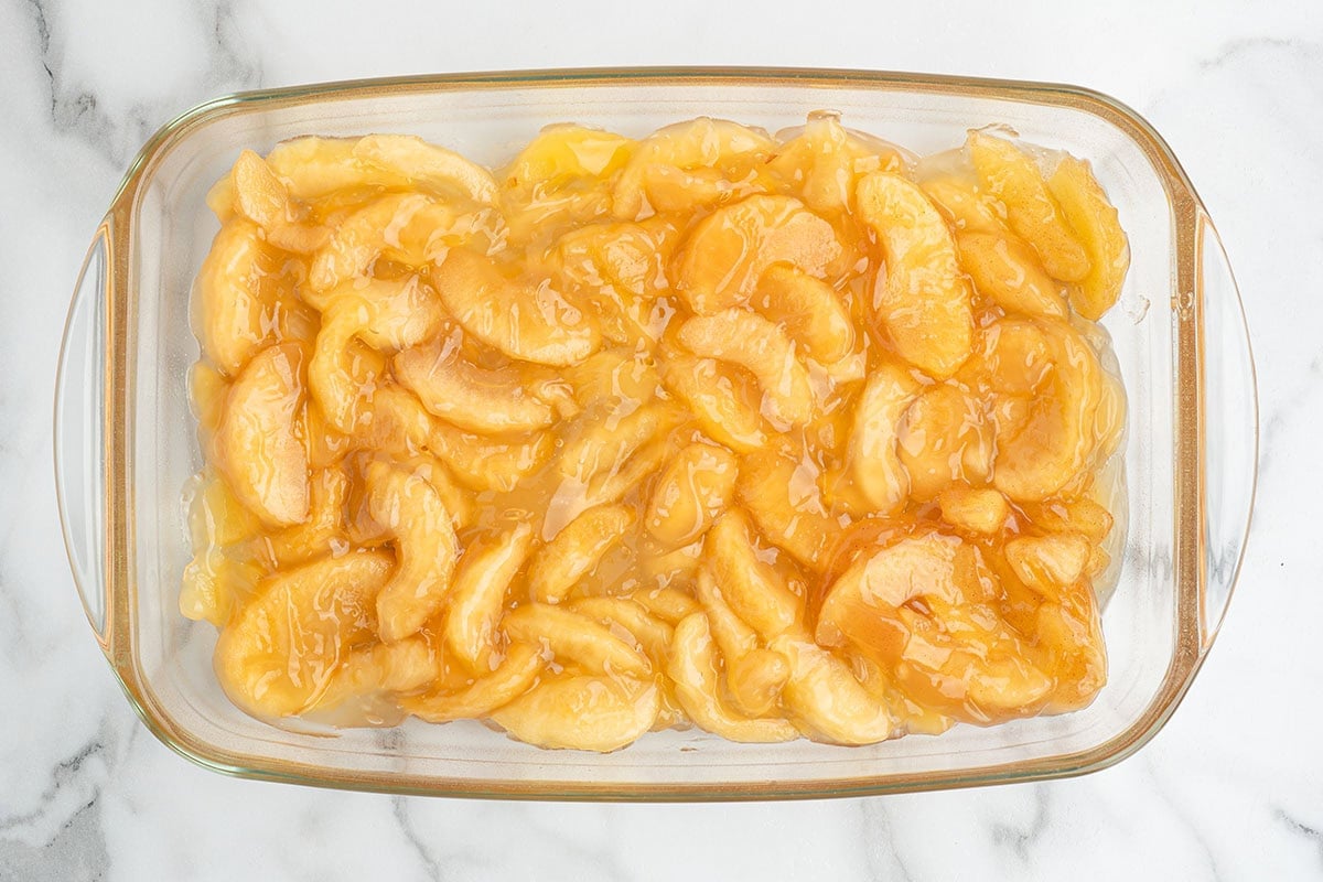 Sliced apples in caramel sauce in a glass baking dish.