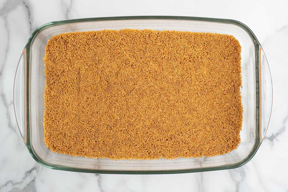 Graham cracker crumb crust pressed into a glass baking dish.