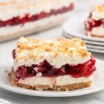 Slice of layered cherry yum yum dessert with graham cracker crust and cream layers.