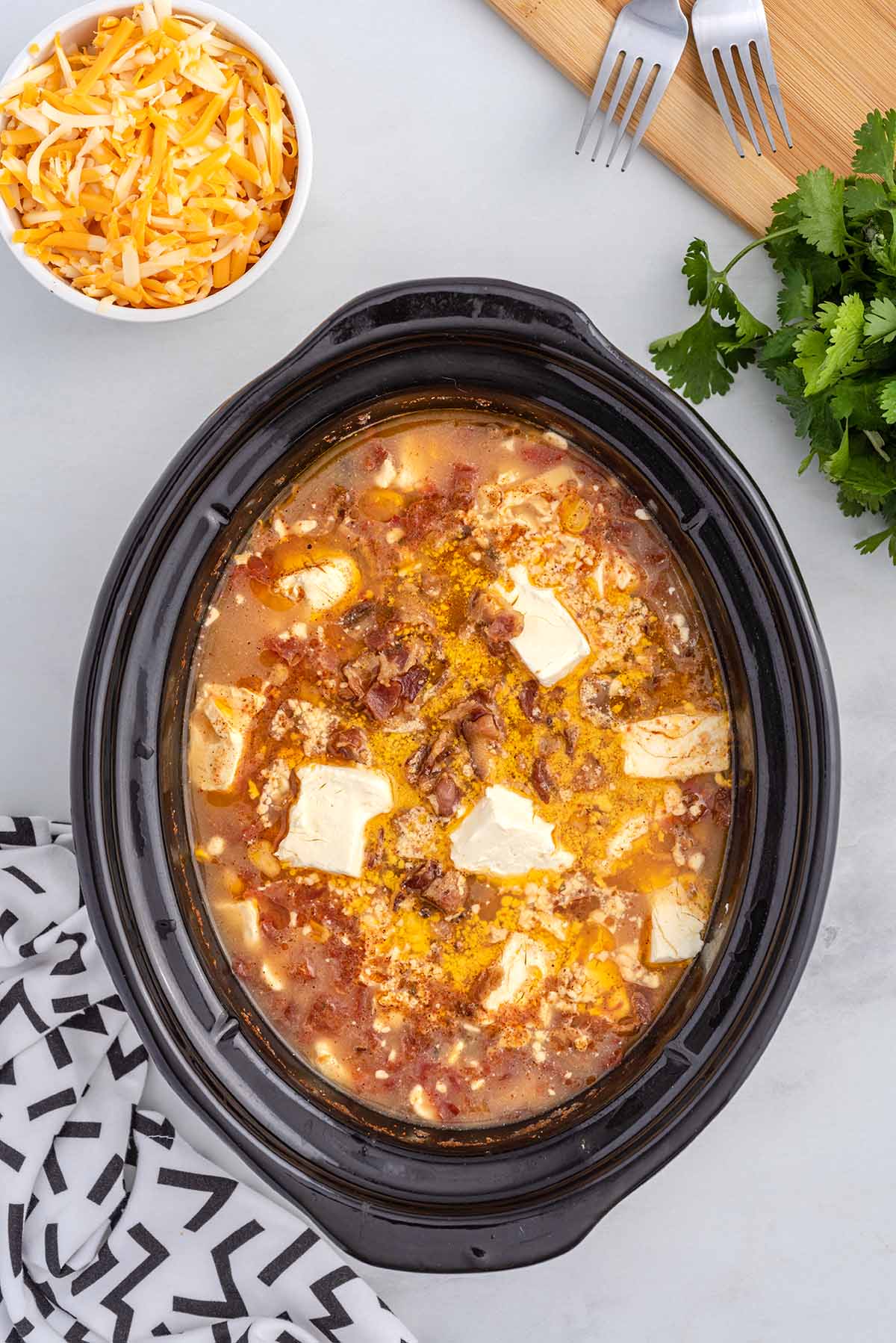 Crack chicken chili cooking in a slow cooker with cream cheese, bacon, chicken, and seasonings.