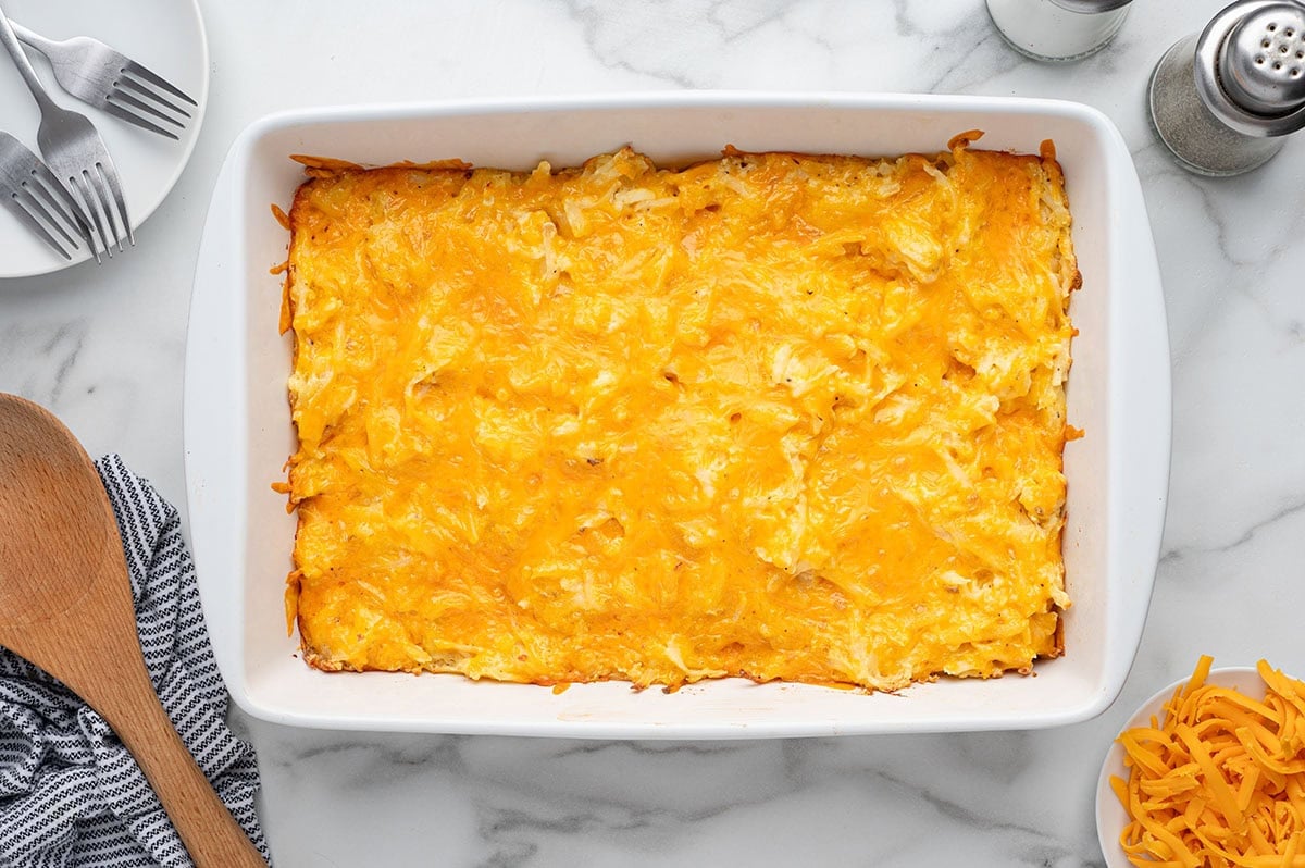 Overhead view of baked hashbrown casserole with melted cheddar cheese in a white dish.