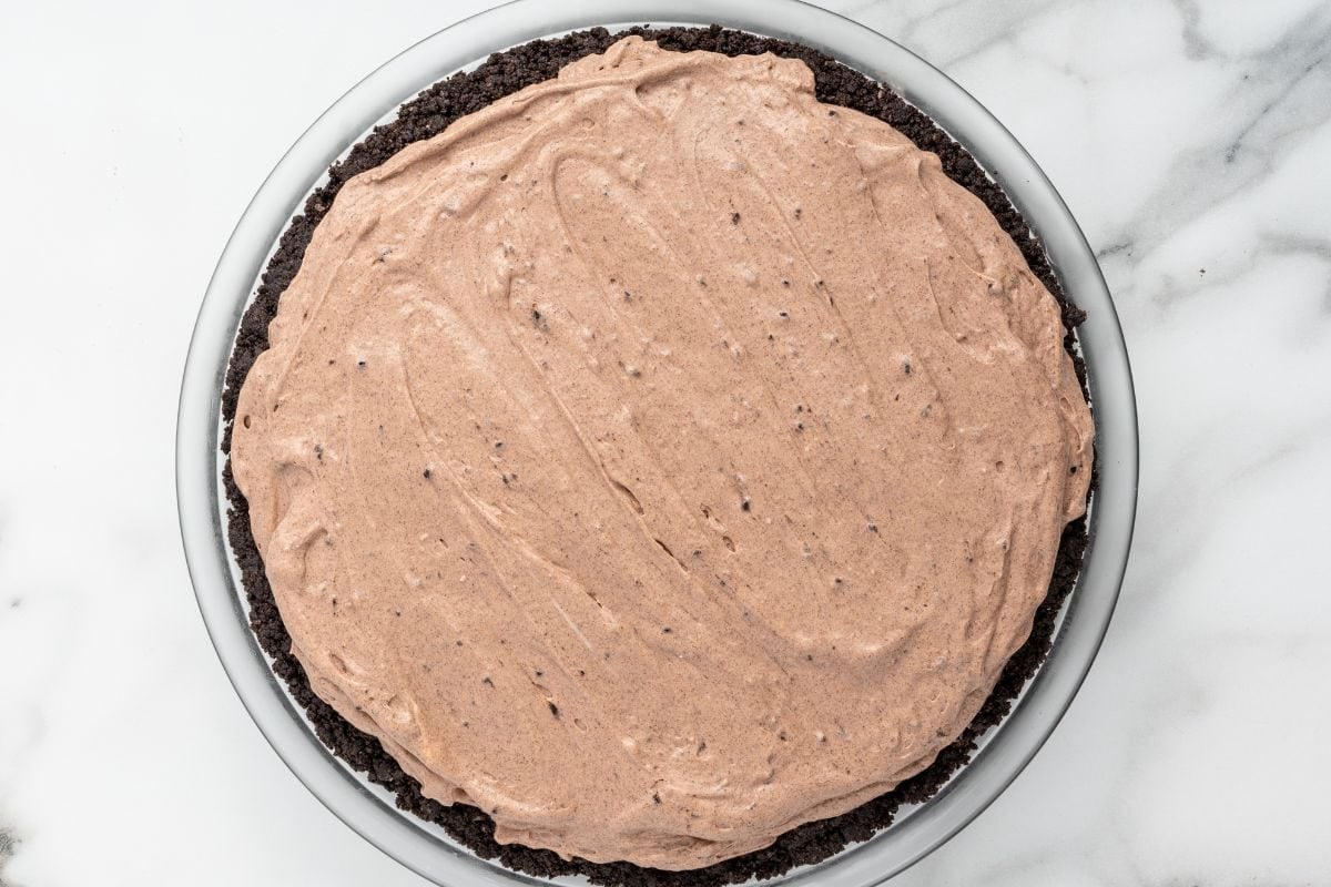 Chocolate cream filling spread over an Oreo crust in a pie dish.