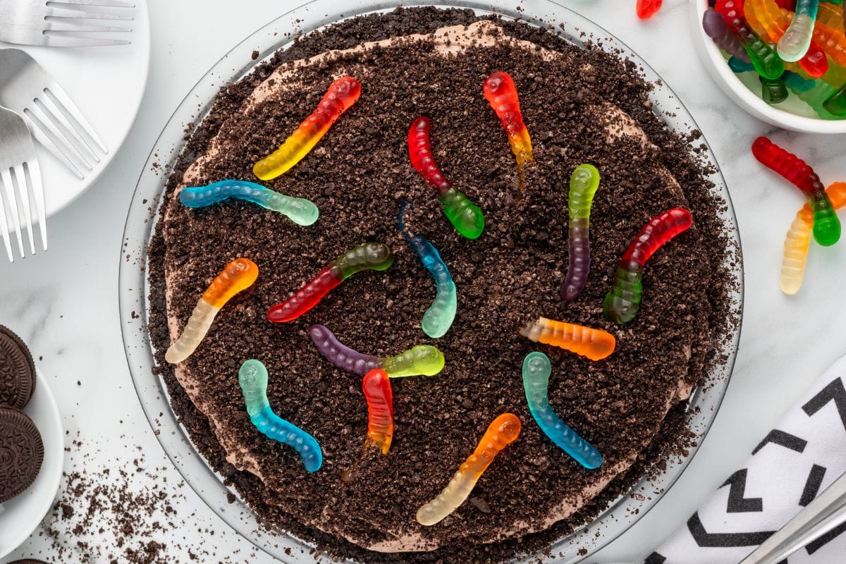 Overhead view of dirt pie topped with crushed Oreos and gummy worms.
