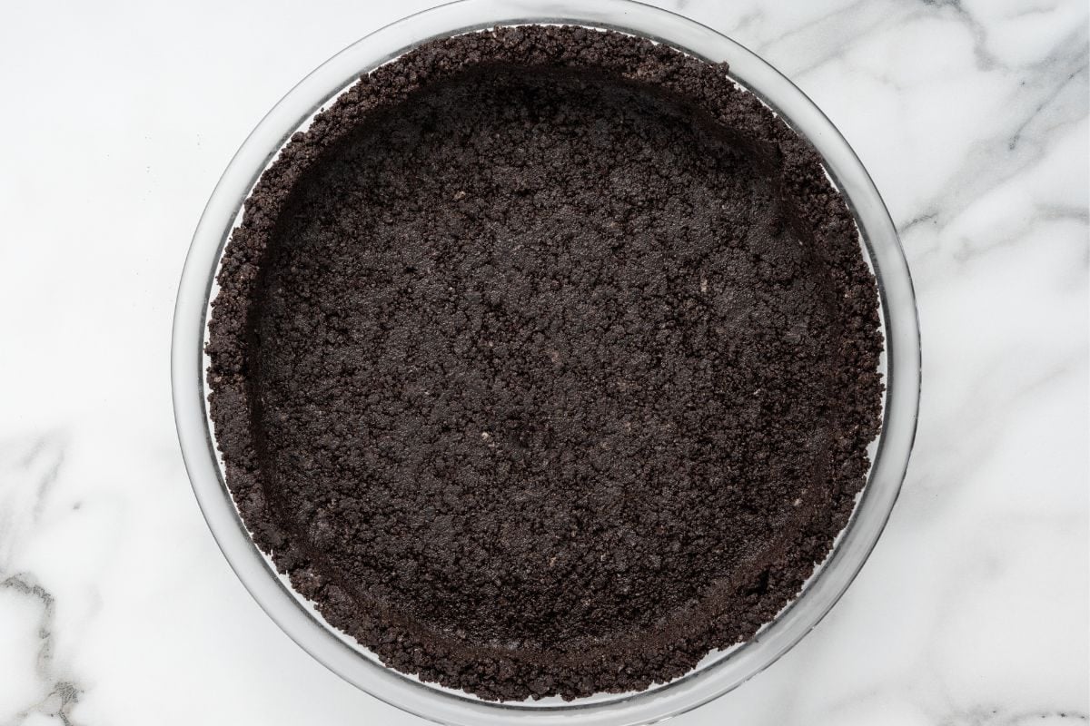 Oreo cookie crumb crust pressed into a glass pie dish.