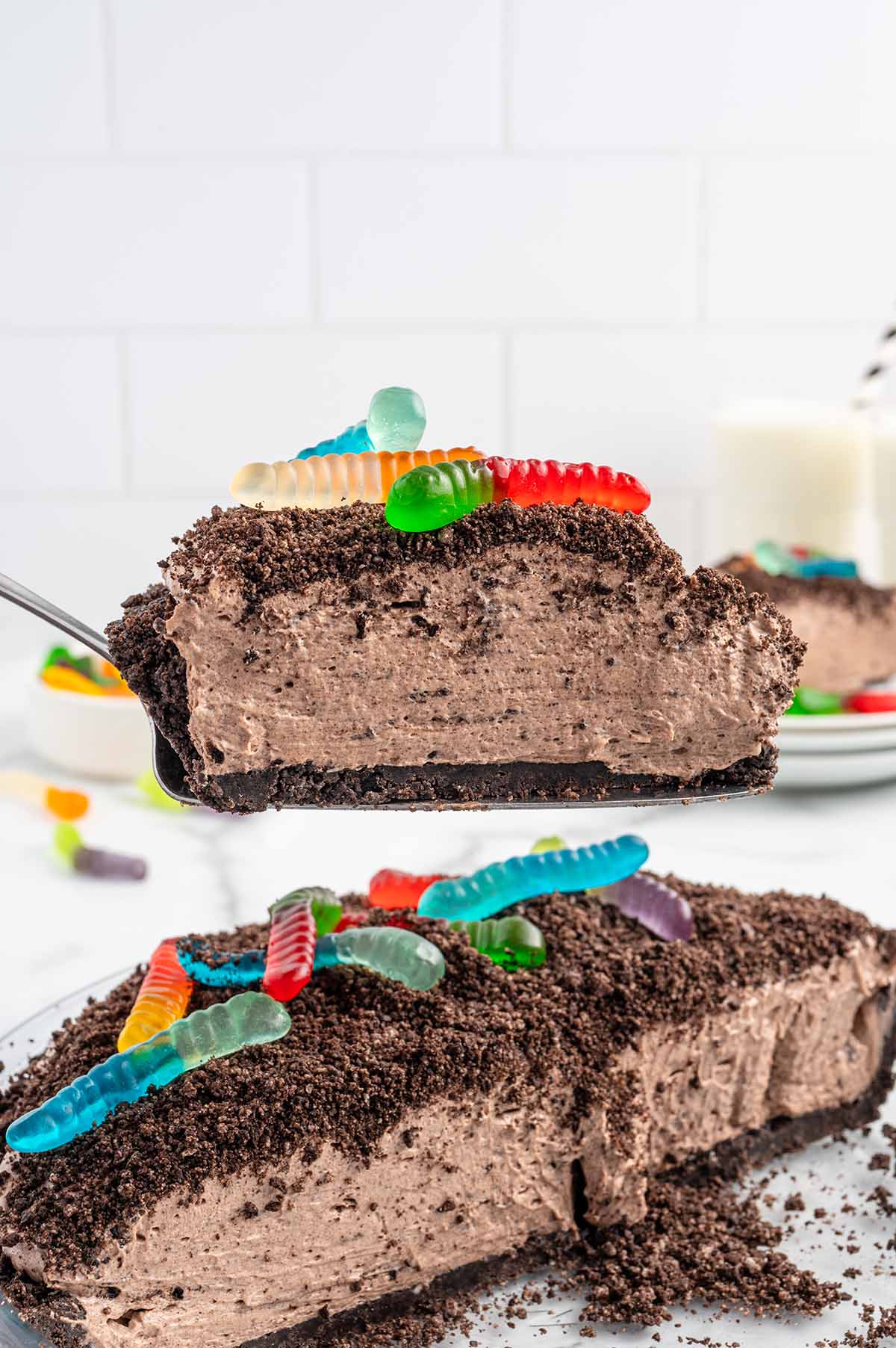 Slice of dirt pie lifted from the pan showing creamy filling, Oreo crust, and gummy worms.