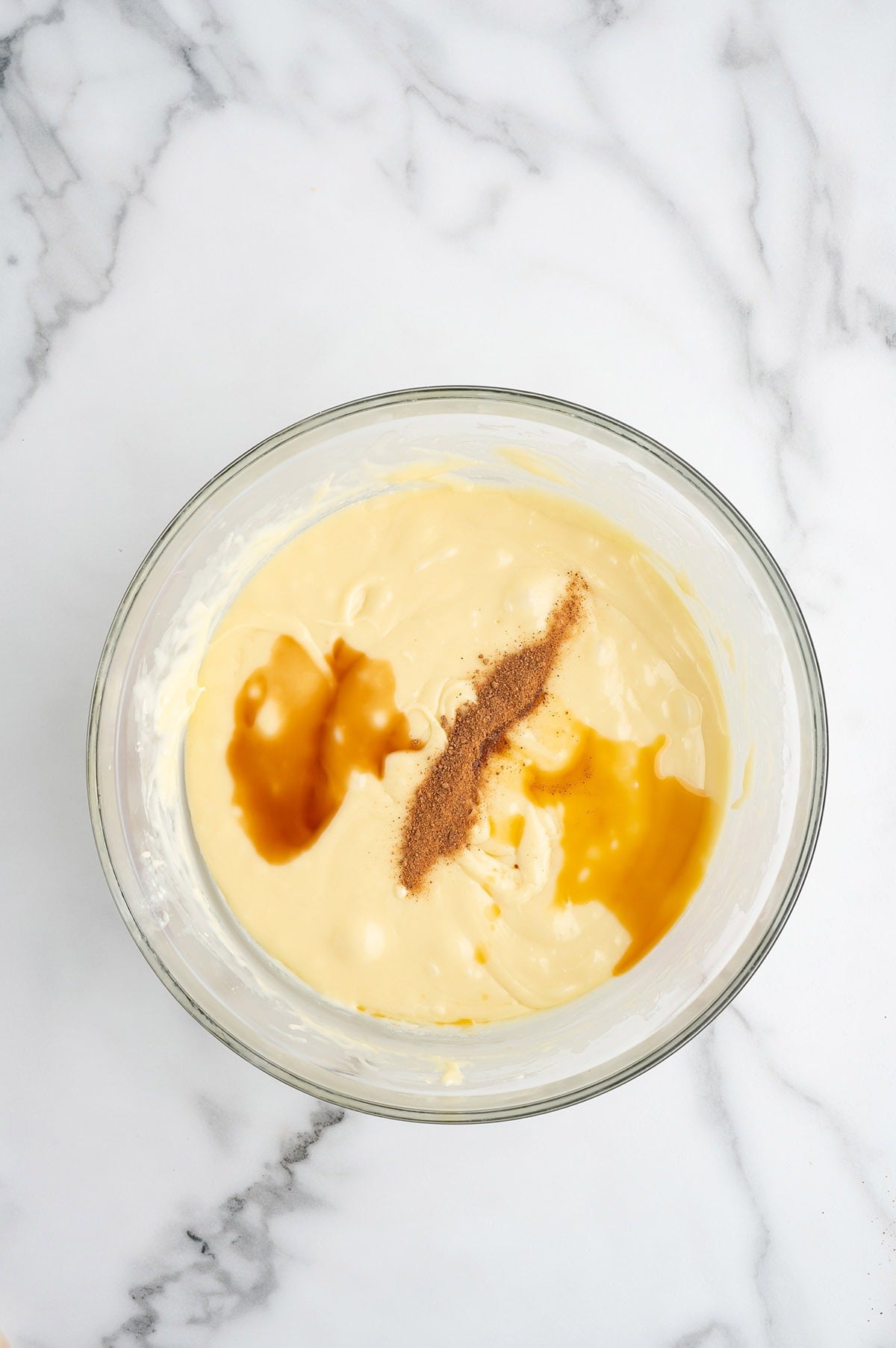Eggnog fudge mixture with vanilla and nutmeg in a glass mixing bowl.